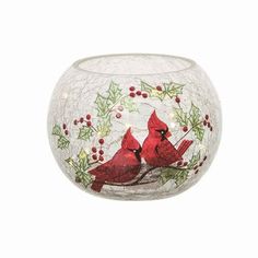 a glass vase with two red birds on it's side and holly berries around the rim