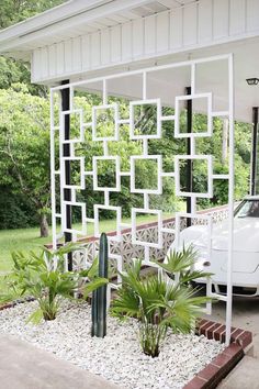 a white car is parked in front of a house with a trellis on it