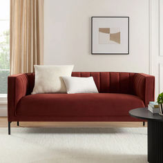 a living room scene with focus on the red couch and white pillows, along with a black coffee table