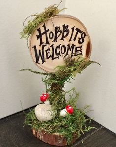 a wooden sign that says, hobbits welcome with mushrooms and moss on it