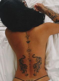 a woman laying in bed with her back turned to the camera and tattoos on her body