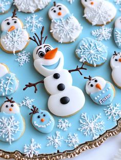 frosted cookies decorated like snowmen are on a blue platter with white icing