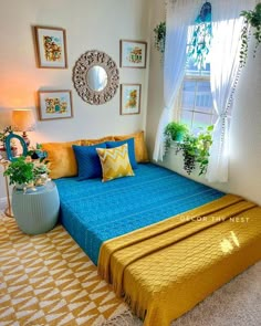 a blue and yellow bed in a room with pictures hanging on the wall above it