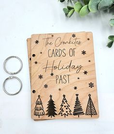 a wooden christmas card with the words cards of holiday past on it next to two silver rings