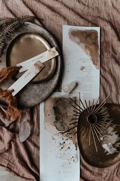 dirty dishes and papers on a bed with brown sheets in the background, including an old fan