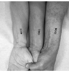 two people holding hands with small tattoos on their arms and the other hand is in front of them