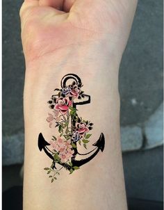 an anchor and flowers tattoo on the left wrist is shown in black ink with pink roses