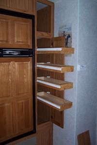 an empty pantry with wooden shelves and drawers on the wall next to a closed door