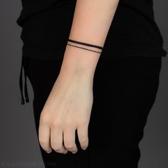 a woman wearing a black bracelet with a cross on it's left wrist and the word love is written across her arm