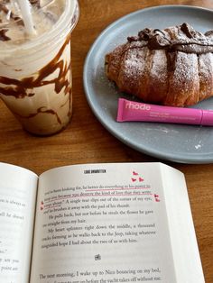 an open book sitting on top of a wooden table next to a cup of coffee