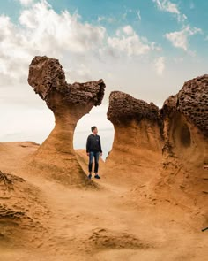 a man is standing in the middle of some sand dunes with rocks on each side