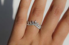 a woman's hand with a diamond ring on top of her finger and the bottom half of her wedding band