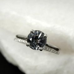 a diamond ring sitting on top of a white cloth covered pillow in the middle of a room