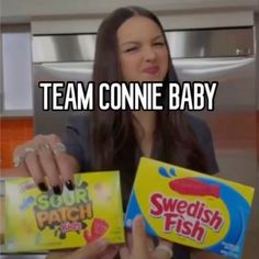 a woman holding two boxes of swedish fish and one box of sweet potato chips with the caption team connie baby