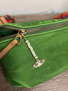 a green purse with a butterfly keychain hanging from it's front pocket