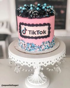 there is a pink cake with black and blue sprinkles on the top