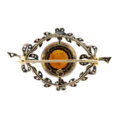 This exquisite Edwardian brooch is a true work of art that will catch the eye of anyone who sets their sights on it. The brooch features a stunning bow and foliate motif, with a central piece that boasts a brilliant cut round citrine, surrounded by a circle of rose cut diamonds. The brooch is further adorned with rose cut and old cut diamonds, arranged in a beautiful bow foliate motif. The mount is made of silver topped yellow gold, which adds an extra touch of elegance and sophistication. On th Elegant Round Brooch With Intricate Design, Elegant Round Brooches With Intricate Design, Luxury Round Brooches For Collectors, Luxury Round Collectible Brooches, Victorian Yellow Gold Brooches With Gemstone, Antique Jeweled Brooches For Formal Occasions, Luxury Round Cabochon Brooch, Luxury Cabochon Brooch, Luxury Round Cabochon Brooches