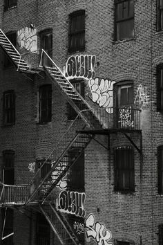 black and white photograph of graffiti on the side of a brick building in new york city