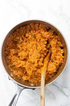 a pan filled with food and a wooden spoon next to it on top of a white counter