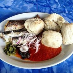 a white plate topped with meat and veggies covered in sauce on top of a blue table