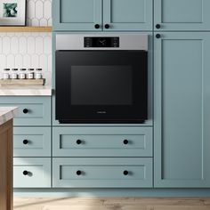 a kitchen with blue cabinets and an oven on the wall, in front of a counter