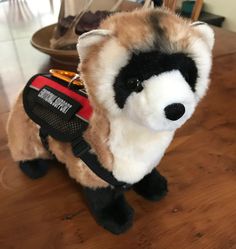 a stuffed raccoon is sitting on the floor with a harness around it's neck