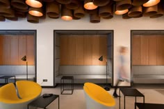 the interior of a modern office with yellow and white chairs, black tables and wooden partitions