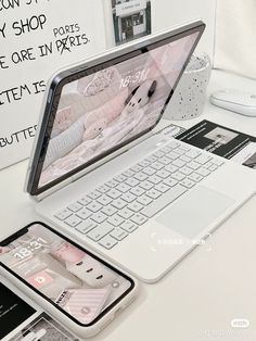 an open laptop computer sitting on top of a white desk next to a cell phone