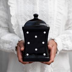 a person holding a black and white polka dot covered container