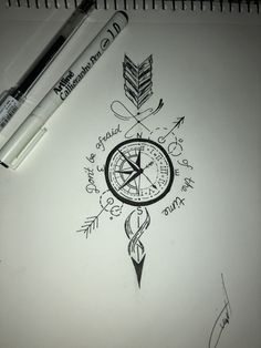 a drawing of a compass and arrows with writing on paper next to a marker pen