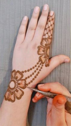 a woman is getting henna done on her hand and the scissors are next to it