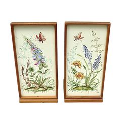 two framed paintings with flowers and butterflies on them, one is painted in white and the other