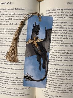 a bookmark with an image of a black dragon on it and tassels