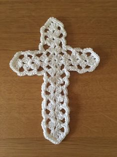 a crocheted white cross sitting on top of a wooden table