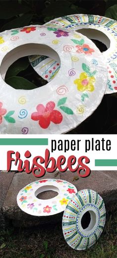 paper plate frisbees sitting on the ground next to some grass and flowers