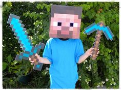 a young boy in a minecraft costume holding up two paper machs with their hands