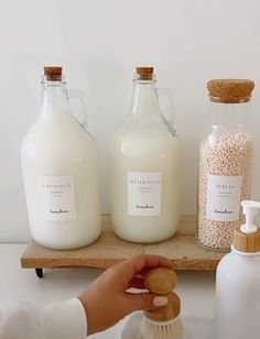 a person is holding a brush near some bottles and soaps on a wooden shelf