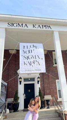 two women standing in front of a building with a sign that says, please your stigma kapa