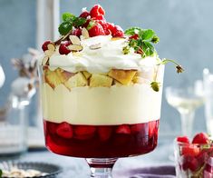 a trifle with strawberries and whipped cream in a glass dish on a table