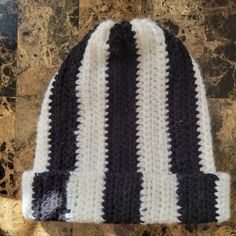 a black and white striped knitted hat sitting on top of a marble countertop