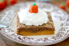 a piece of cake on a plate with whipped cream and an orange carrot on top