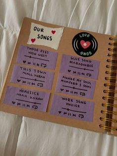 an open notebook with stickers on it and some writing in the pages that read our songs