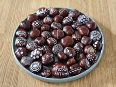 a bowl full of chocolate hearts with the word hello autumn written in white on them