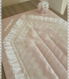 a baby's crib is covered in pink and white ruffled sheets with lace trim