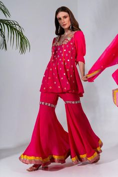 Fuchsia pink mirror, thread and sequin embroidered kurta crafted in georgette, with puffed sleeves and U neckline. Paired with a gharara and dupatta.
Components: 3
Pattern: Embroidered
Type Of Work: Applique, Sequin, Thread, Mirror
Neckline: U Neck
Sleeve Type: Puffed
Fabric: Kurta and Gharara: Georgette, Dupatta: Organza
Color: Fuchsia
Other Details: 
Length:
Kurta: 32 inches
Gharara: 42 inches
Occasion: Mehendi and Haldi - Aza Fashions Designer Pink Sharara With Dori Work, Diwali Pink Palazzo Set With Dori Work, Festive Pink Sharara With Gota Work, Pink Sharara For Navratri, Pink Sharara With Dori Work, Pink Gota Work Sets For Diwali, Festive Pink Sharara With Dabka Work, Pink Palazzo Set For Diwali, Festive Pink Sharara