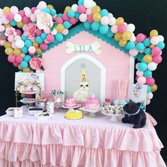 a table topped with cake and balloons next to a small pink house covered in confetti