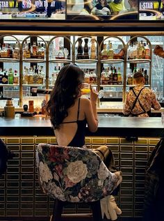 a woman sitting at a bar with her back to the camera