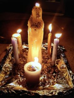 candles are lit in front of a bottle on tin foil with other items around it