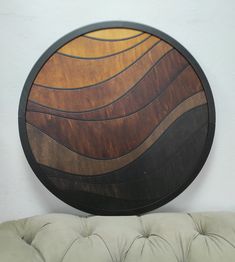 a round wooden wall hanging on the side of a white wall next to a couch