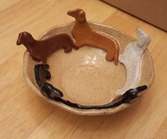 three small ceramic dogs sitting in a bowl